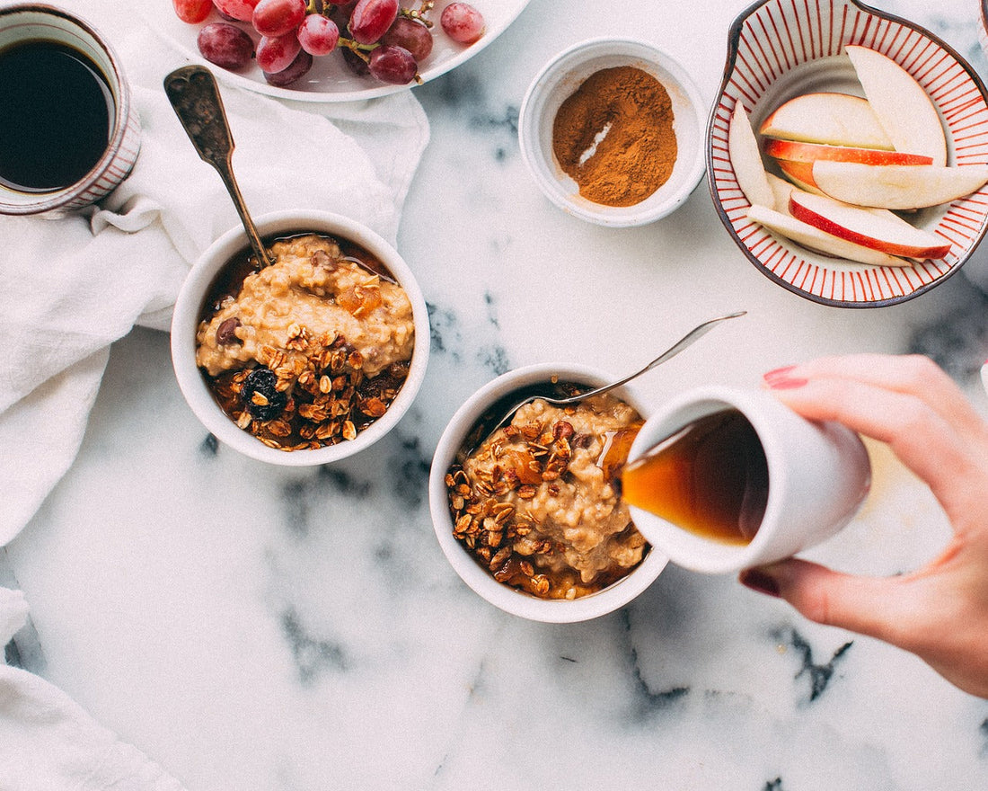 breakfast table with sliced apple, grapes, oats, and honey